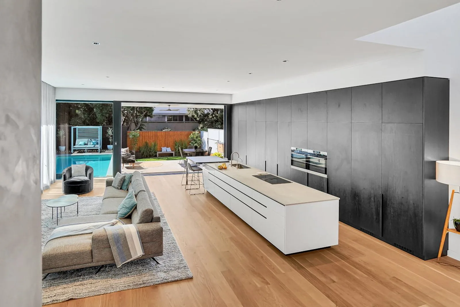 Open-plan kitchen and living area in a new build, with full-height cabinetry and a large island bench