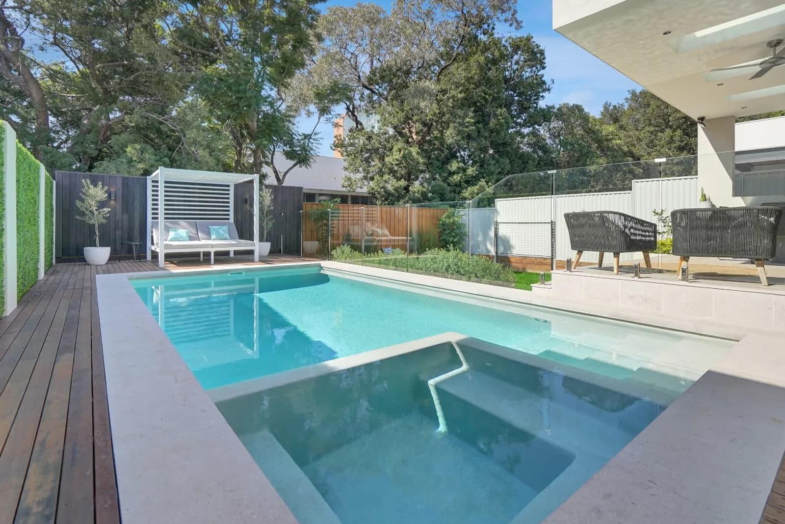 Resort-style in-ground pool with glass fencing, timber decking and a covered entertaining area