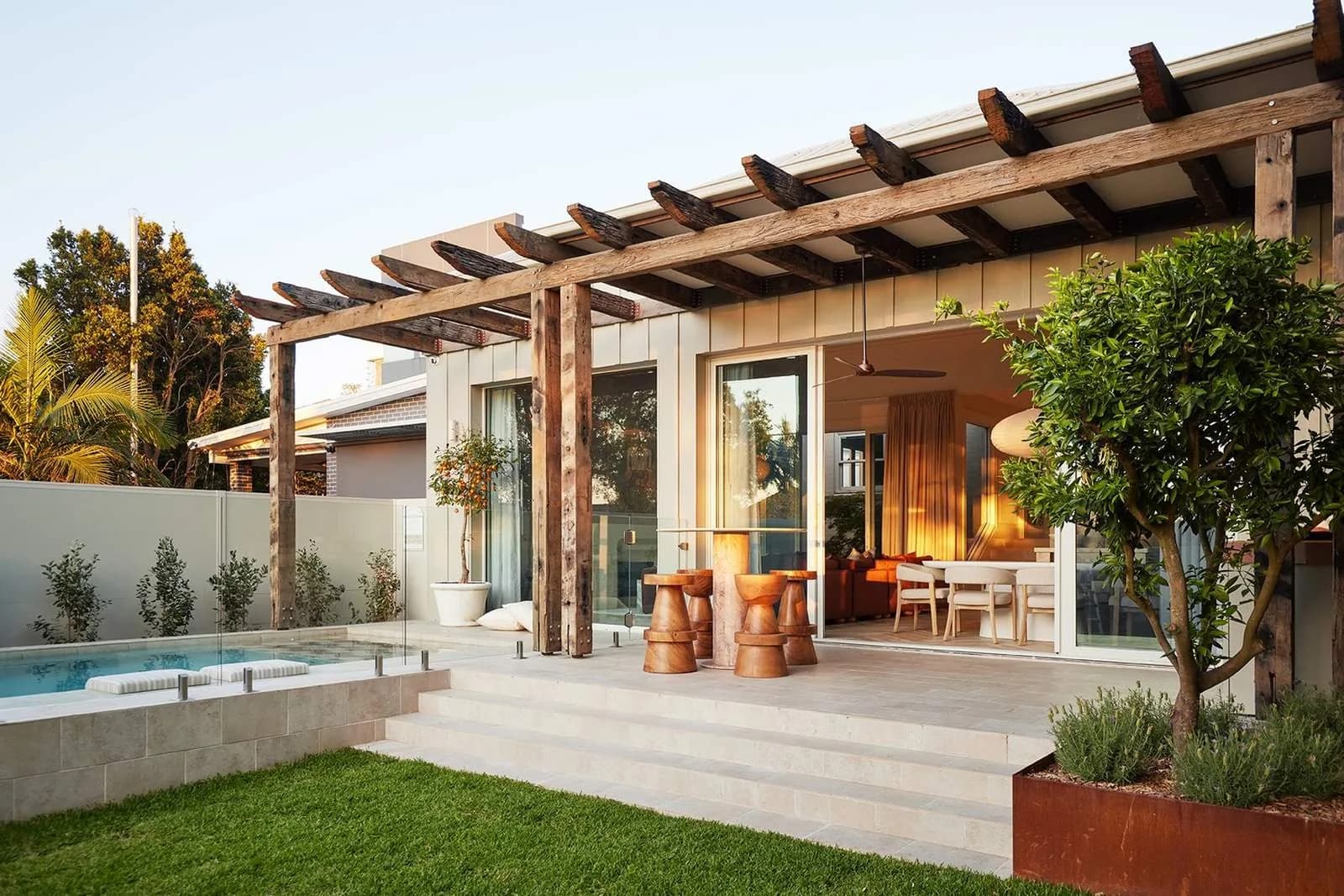 Rear outdoor entertaining area with timber pergola, tiled terrace, pool fencing, landscaped garden and direct connection to the interior living spaces
