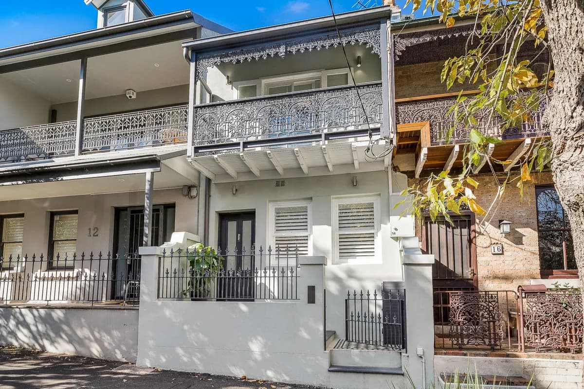 Two-storey inner-city Sydney terrace with a rendered façade, upper-level balcony and traditional iron detailing at the street front